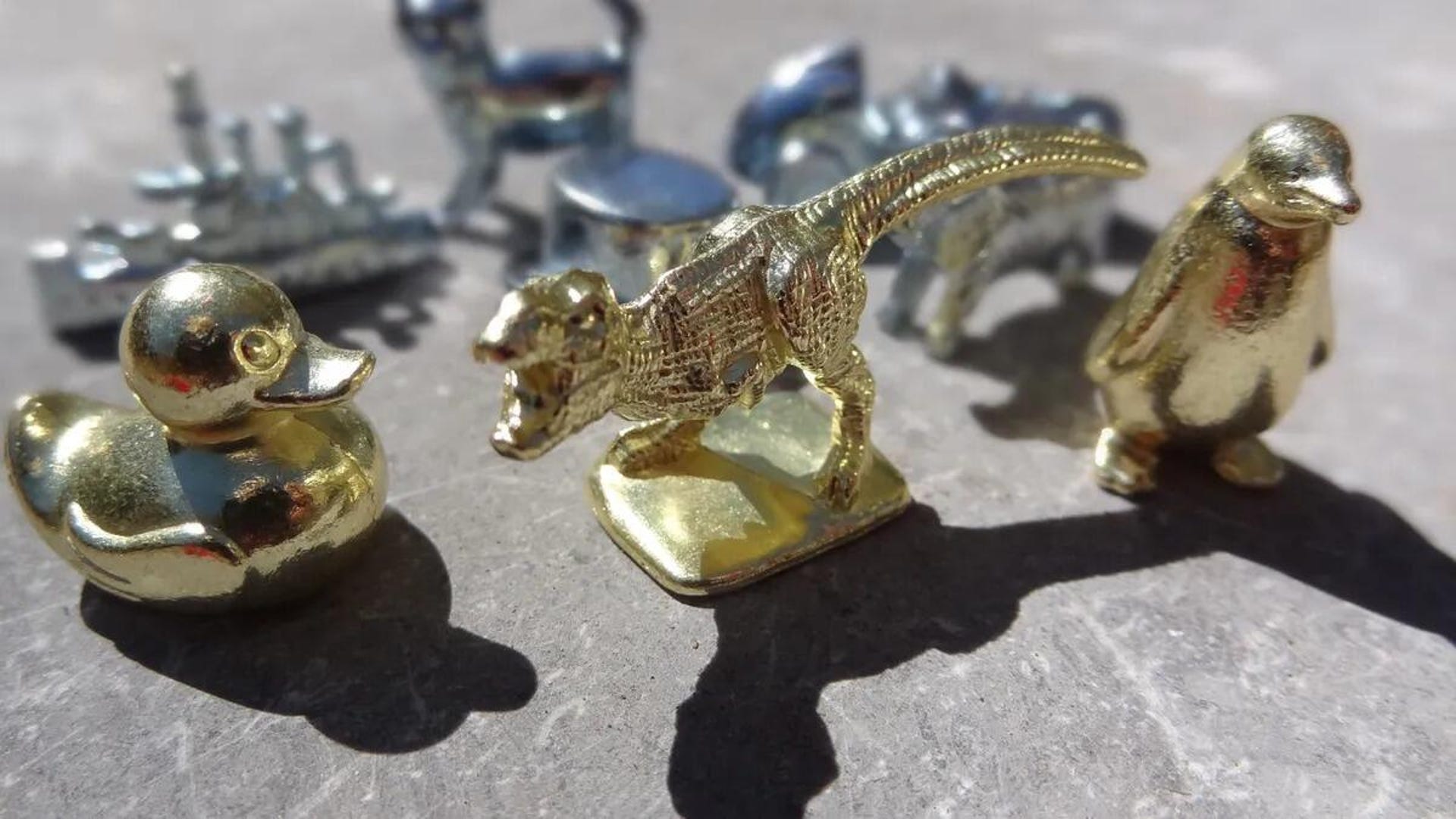 Monopoly tokens including T. rex, duck, penguin, battleship and cat