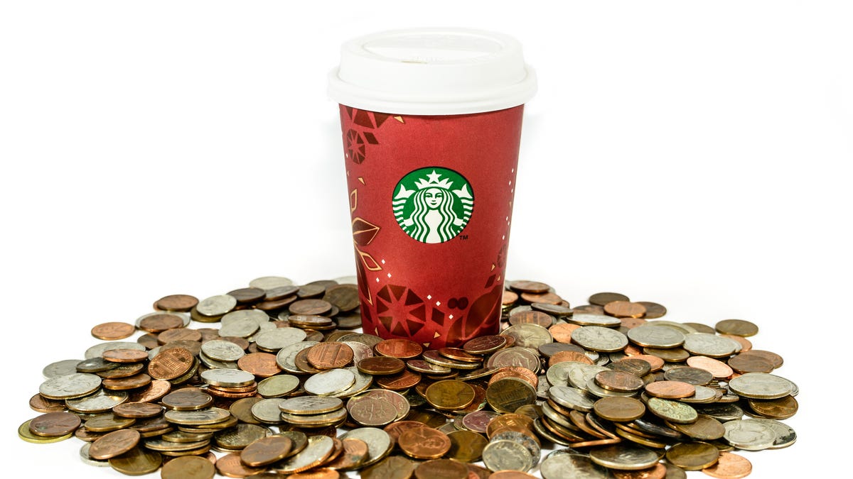 Starbucks cup sitting on mountain of coins