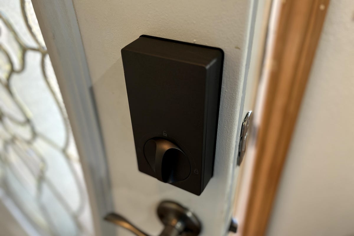 La cerradura inteligente de Aqara muestra la caja de control del cerrojo interior en una puerta blanca.
