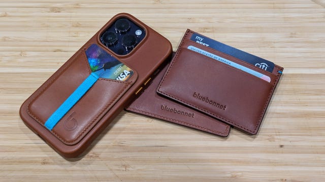 Several brown wallets and an iPhone 14