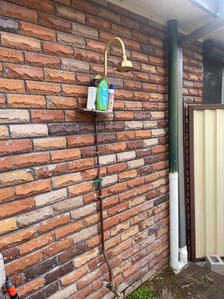 An outdoor shower on a red brick house