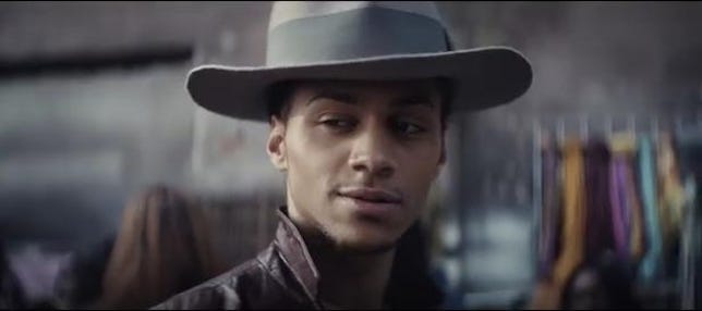 Still from new Apple ad shows man in hat with one eyebrow raised and cool expression on his face