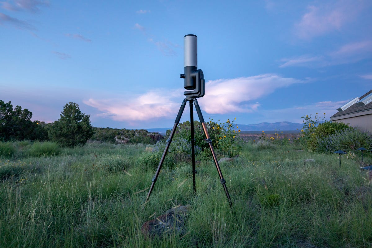 a Unistellar EVscope 2 mounted on its tripod and pointed up toward a blue sky at dusk