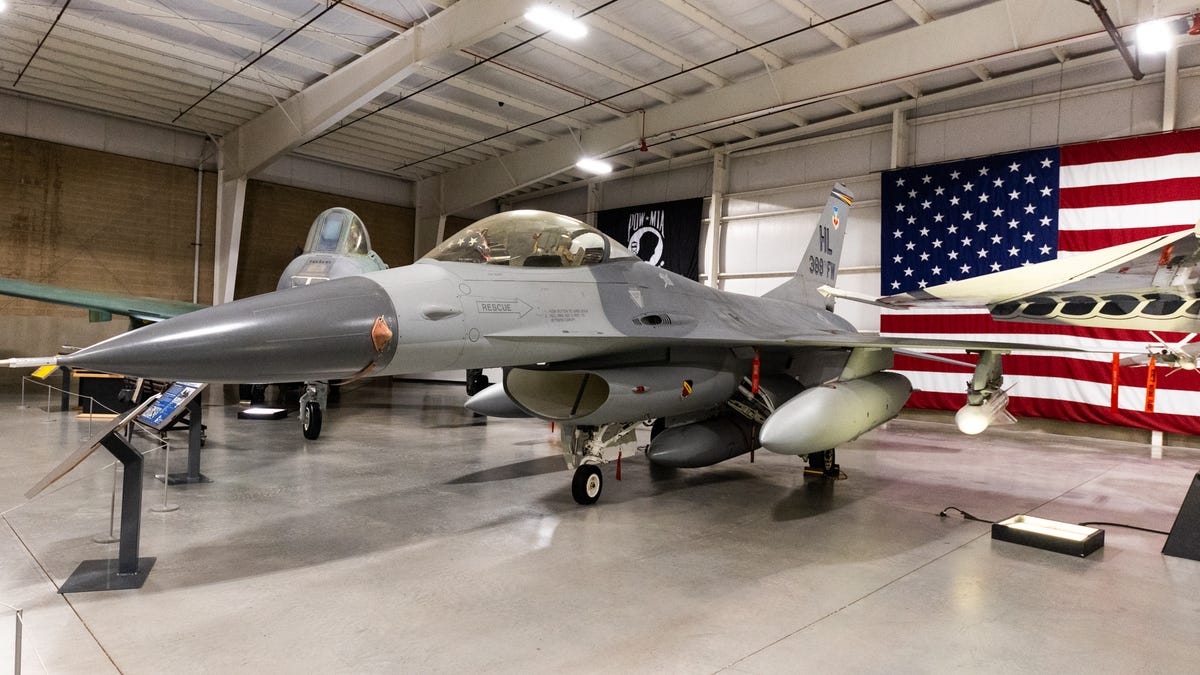The tiny F-16 Falcon in front of an American flag.