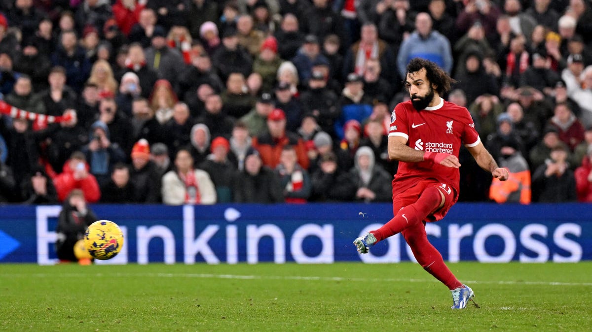 Landscape image of Liverpool forward Mohamed Salah striking a ball with his left foot.