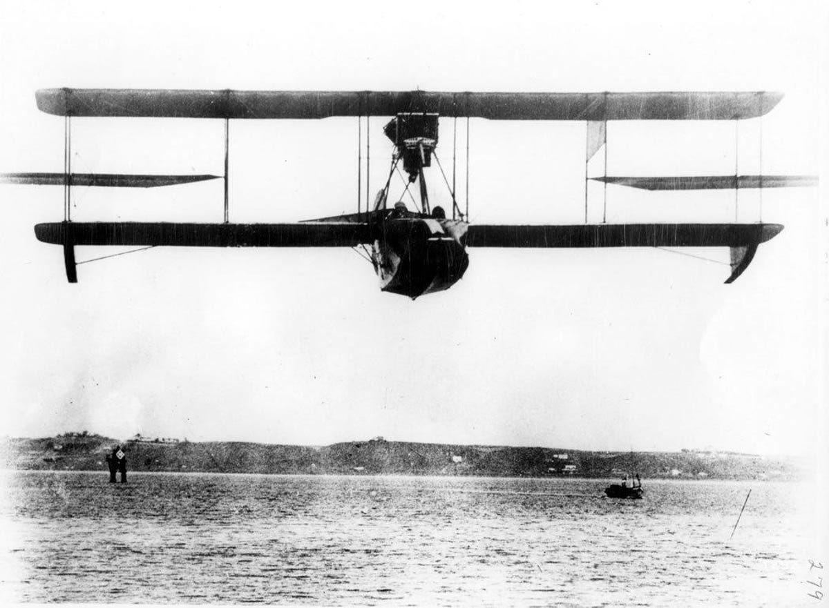 Curtiss flying boat flies low over water