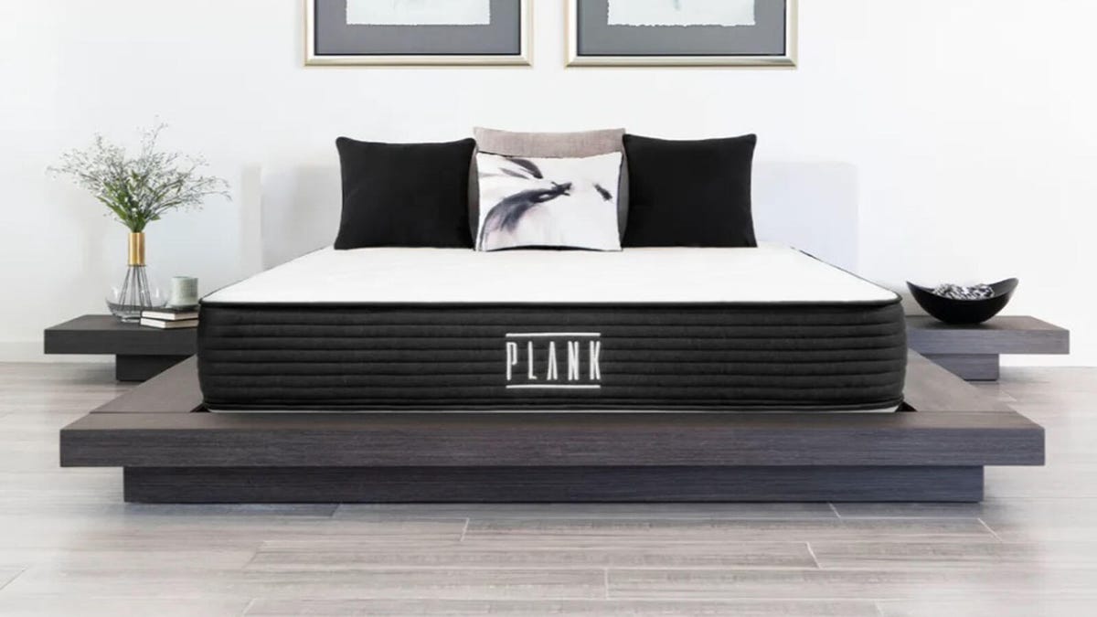 The Plank Firm mattress is displayed on a platform bed in a bedroom.