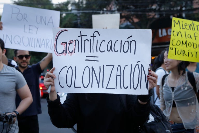 Protesters holding signs, including one that says (in Spanish) 