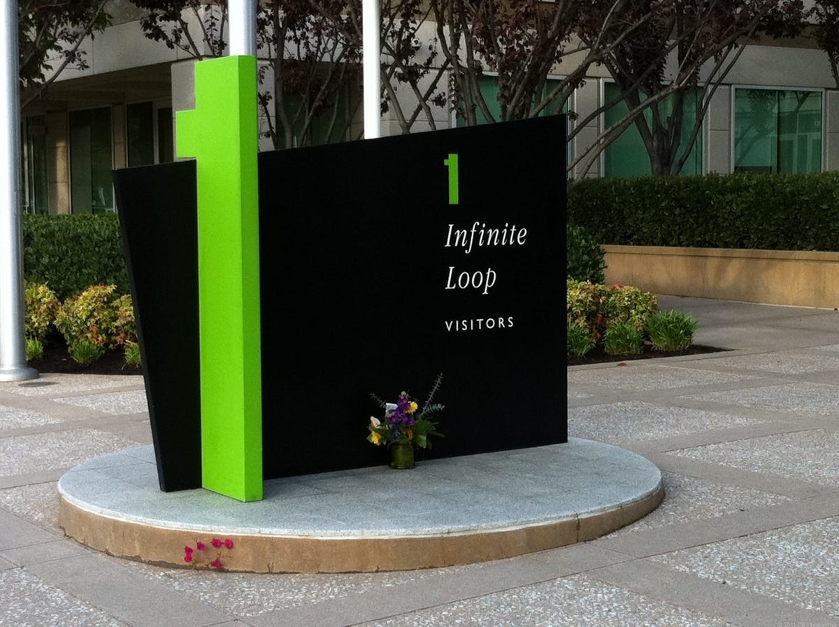 Flowers sit near a sign at Apple headquarters in Cupertino, Calif.