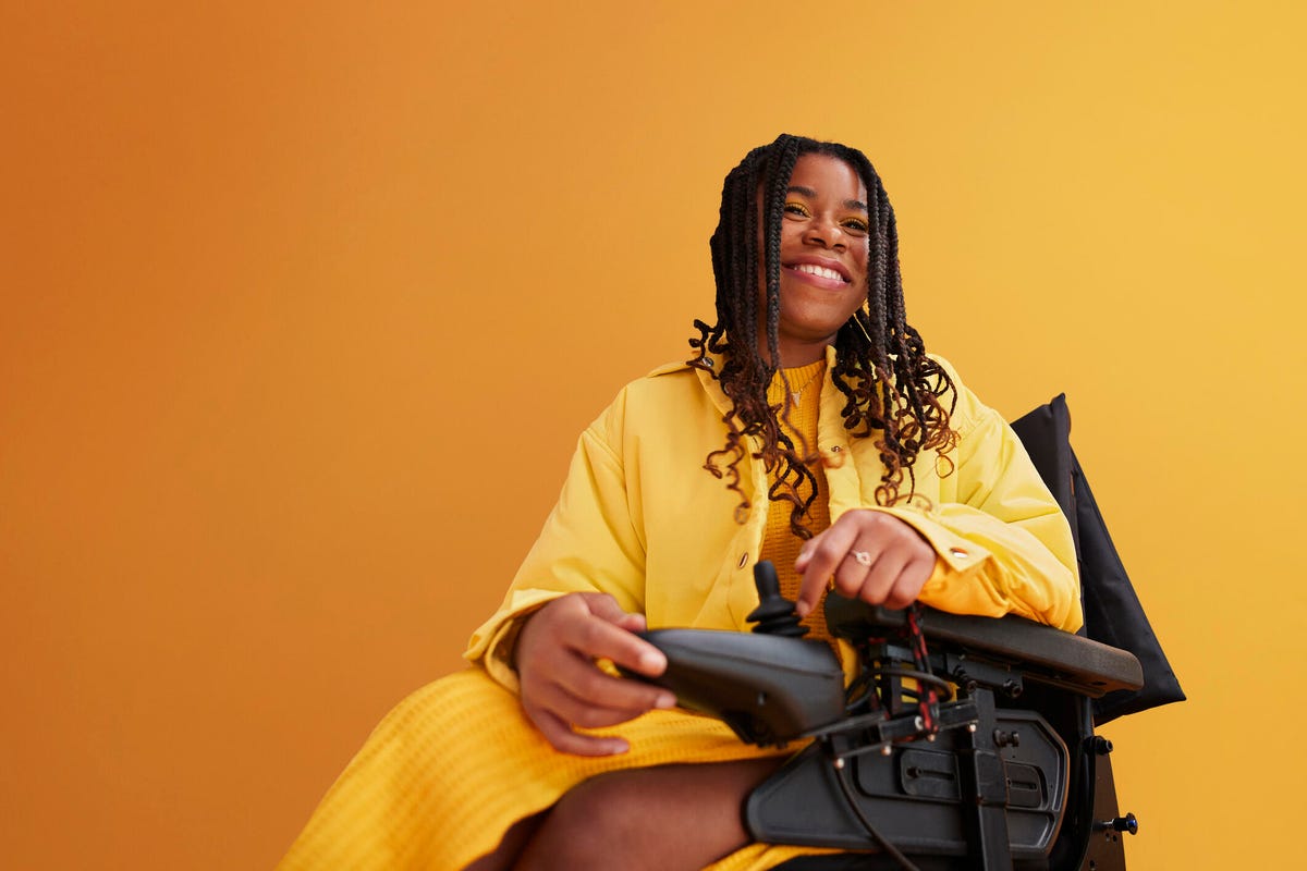 Smiling woman on wheelchair against yellow background