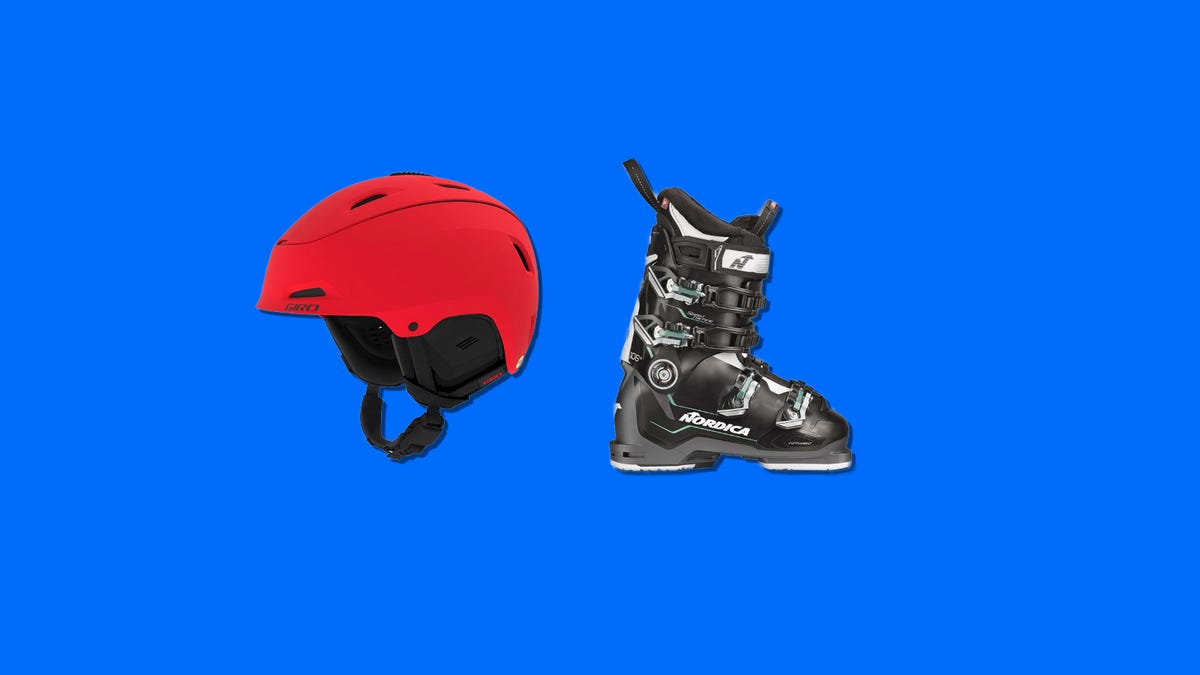 A read ski helmet and black ski boots next to each other on a blue background