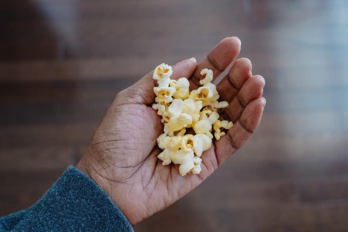 Close-up of a brown hand holding popcorn.