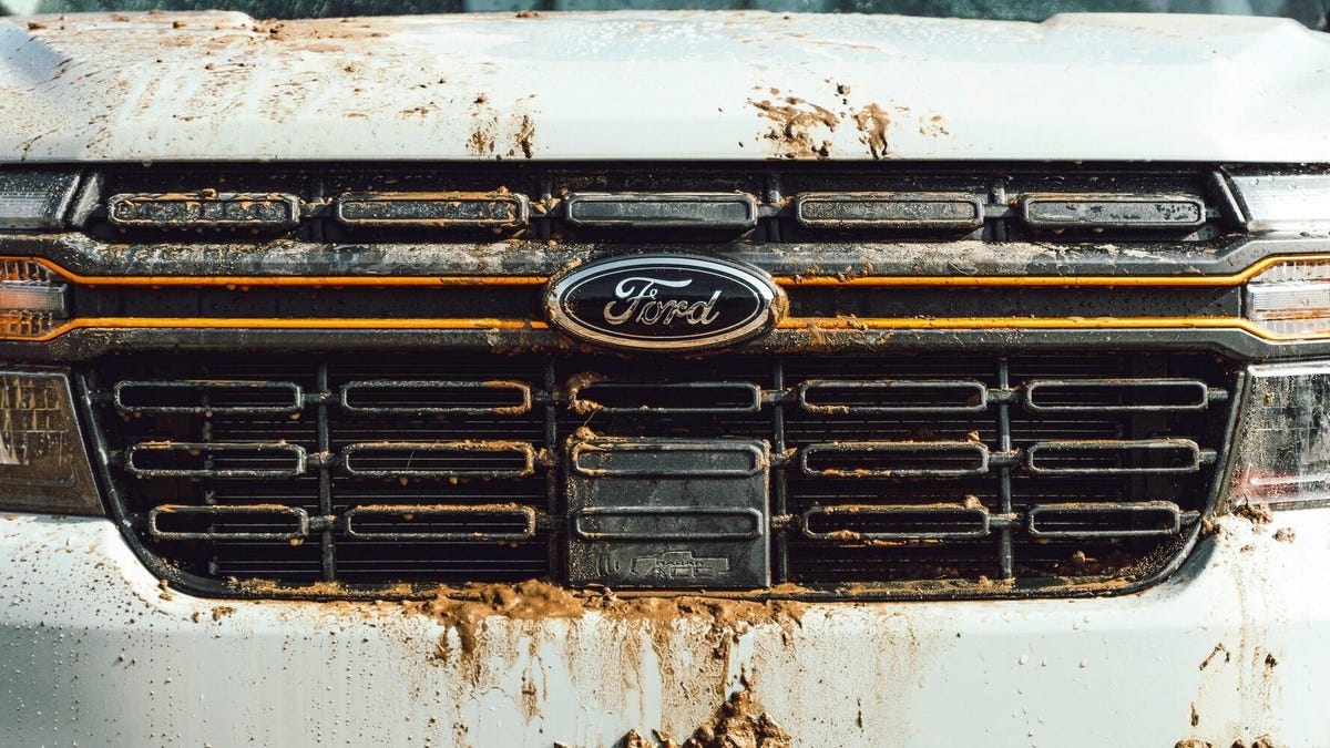 The Ford Maverick Tremor, lifted and looking quite good in gray with orange highlights, playing in a muddy quarry.
