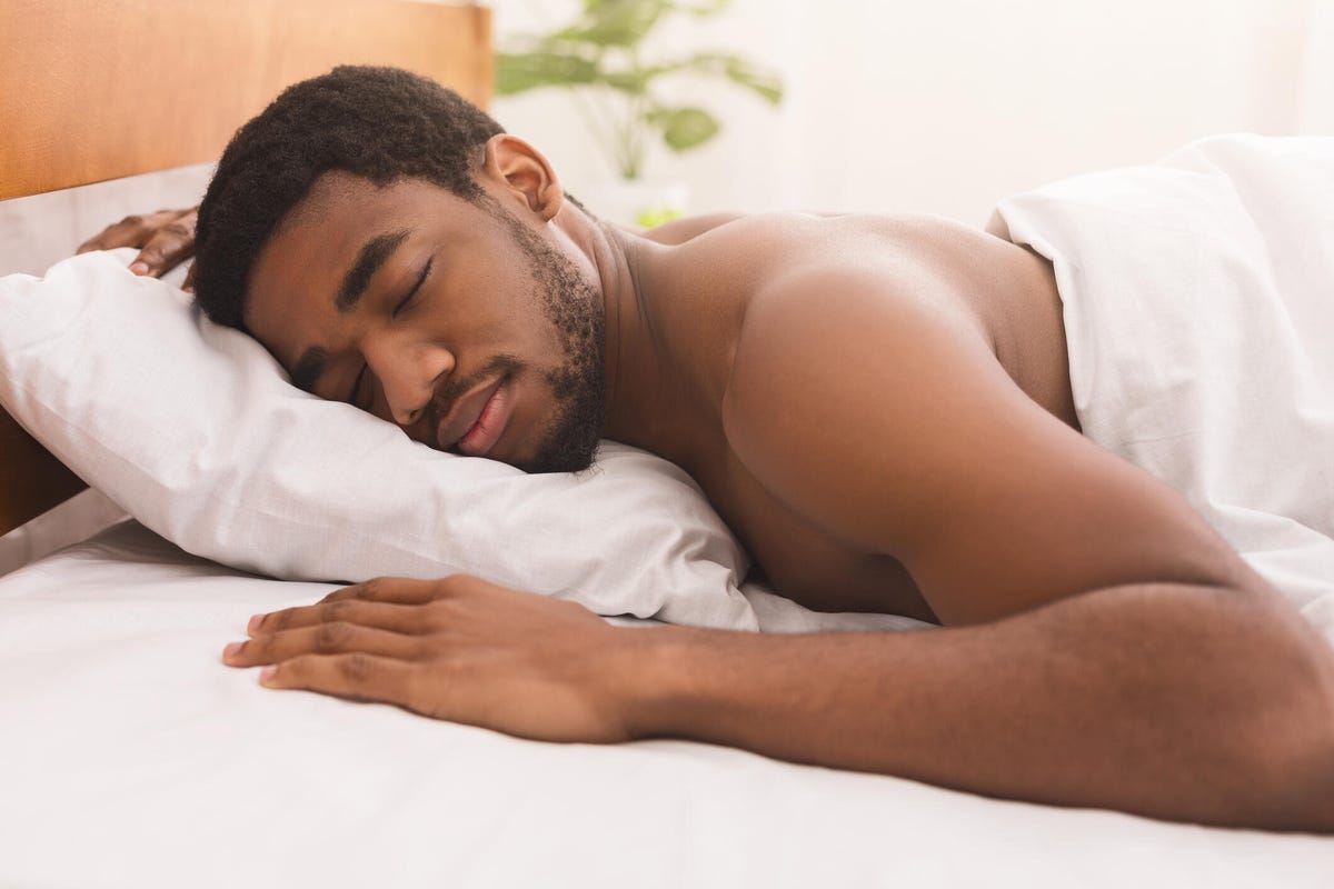 Man sleeping on his stomach in a white bed.