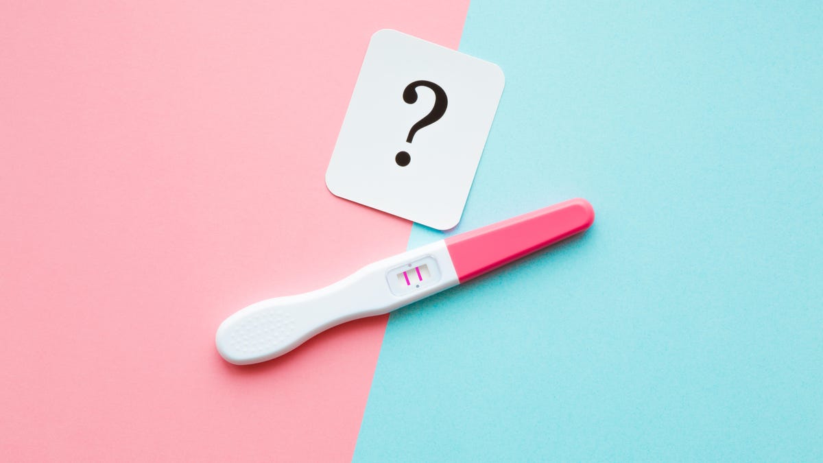 A positive pregnancy test next to a card with a question mark.