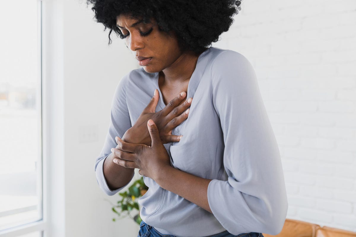 Woman with both hands on top of chest experiencing pain
