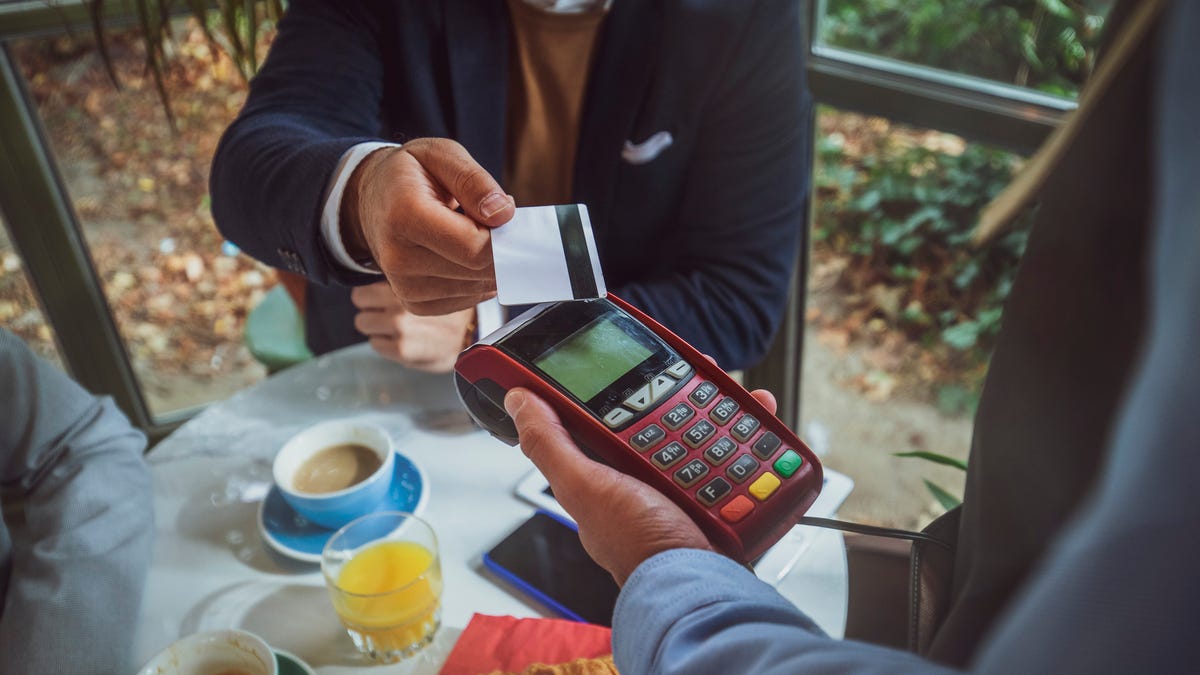 A man is using a credit card to make a contactless payment in public.