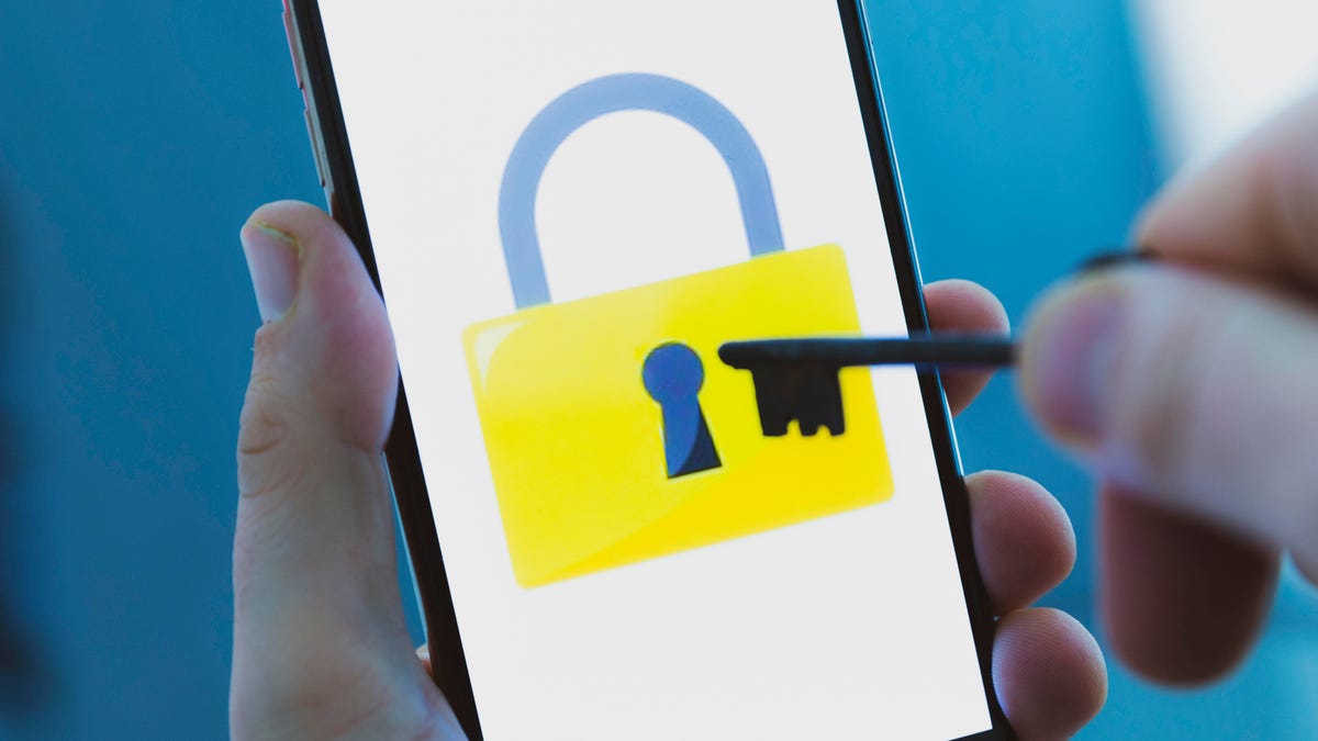 Image of a padlock on a smartphone screen, with someone holding a key.