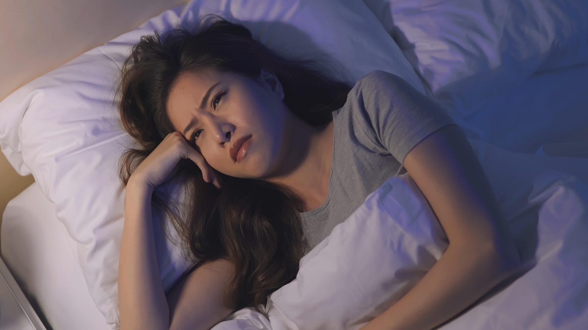 Woman who is laying in bed awake and unhappy about it