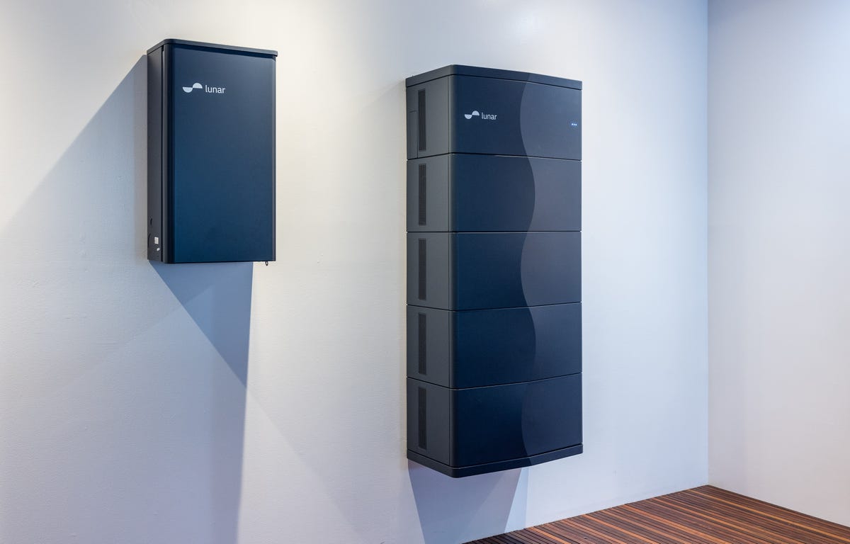 A Lunar Energy battery, a modular system with an S-curve detail down the front panels, is mounted on a white wall