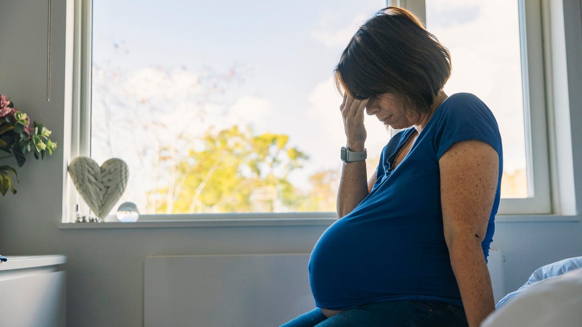 pregnant woman sitting on her bed with pregnant fatigue
