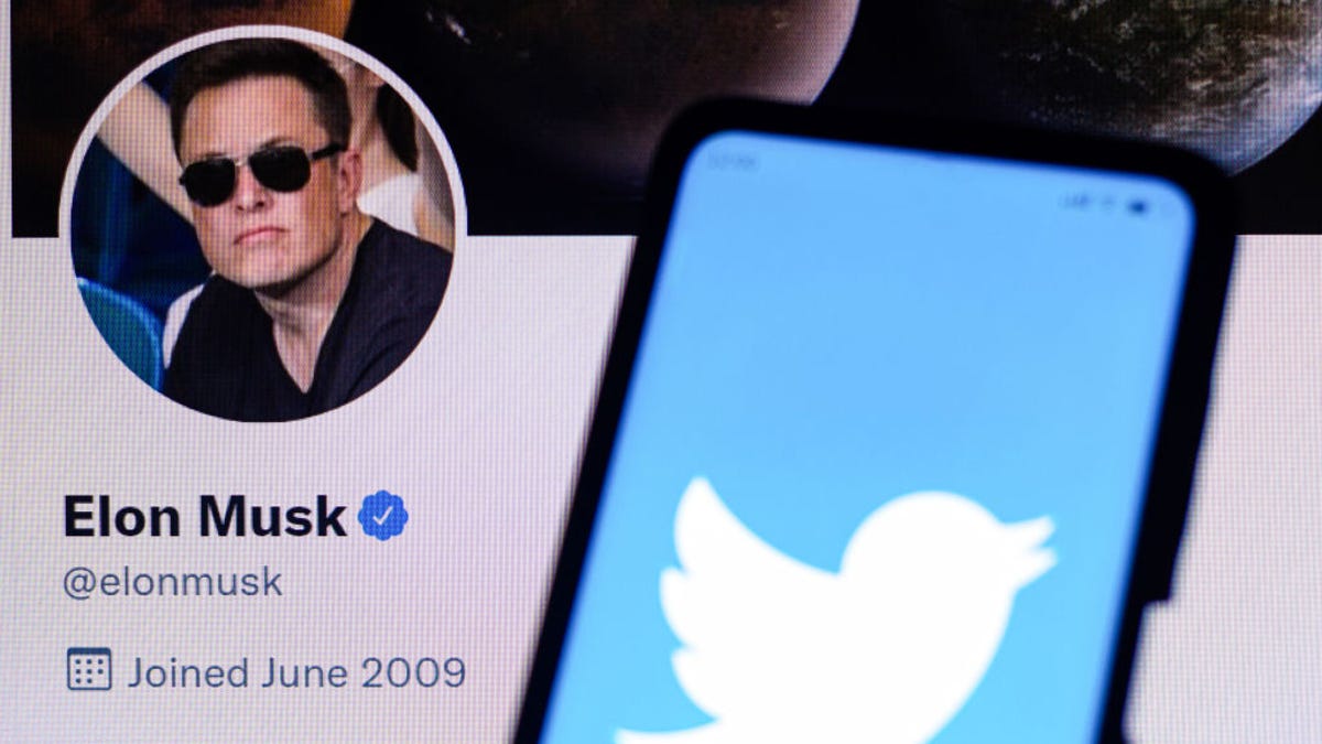 Twitter logo on a phone held in front of Elon Musk's Twitter account page