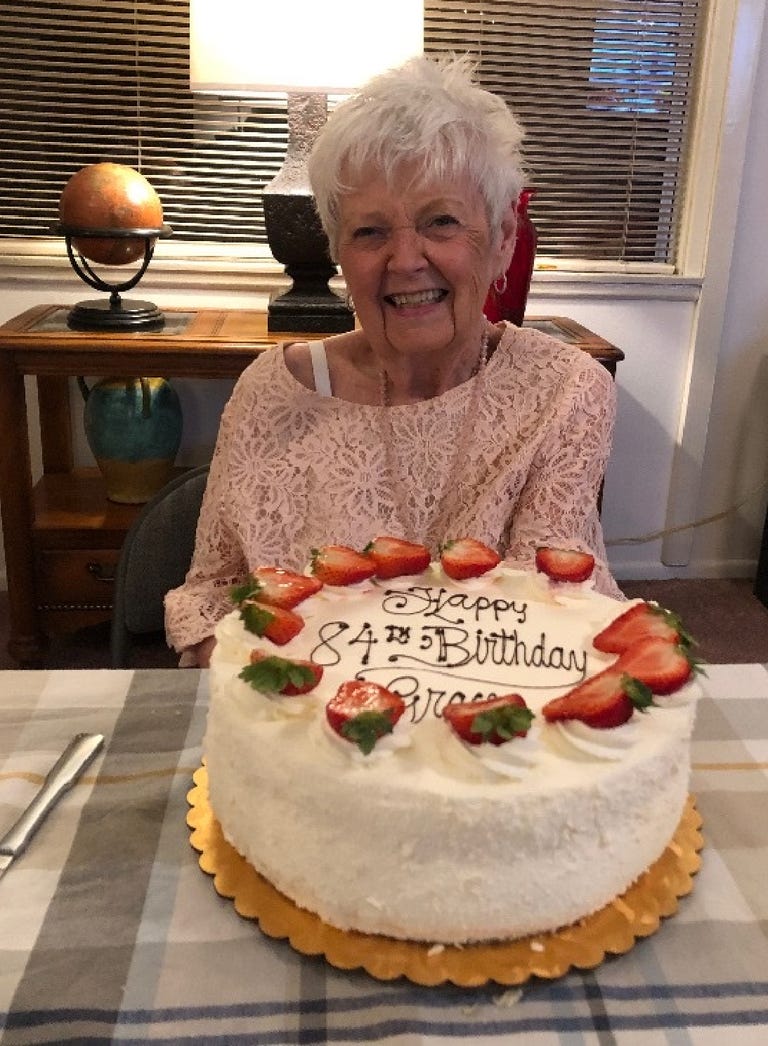 A smiling Grace Peters sits behind a big birthday cake on her 84th birthday