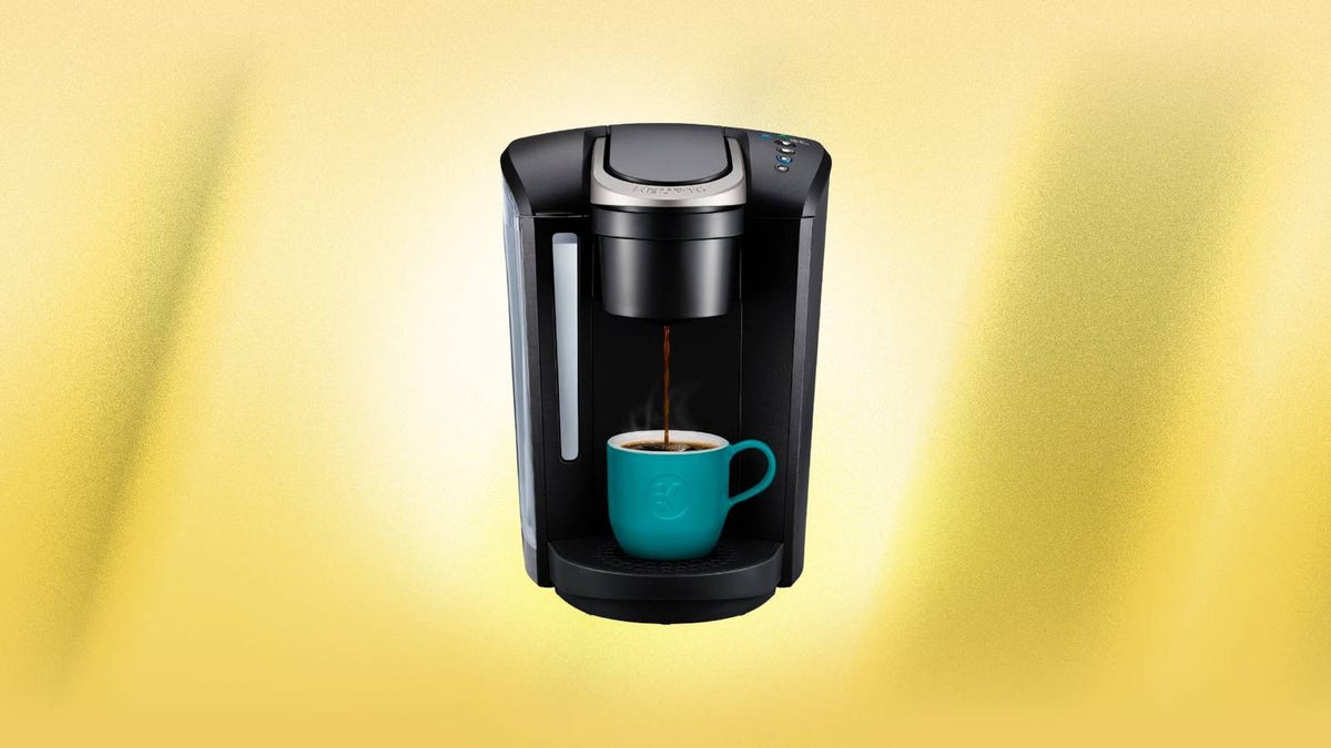 A black Keurig K-Select coffee brewer against a yellow background.
