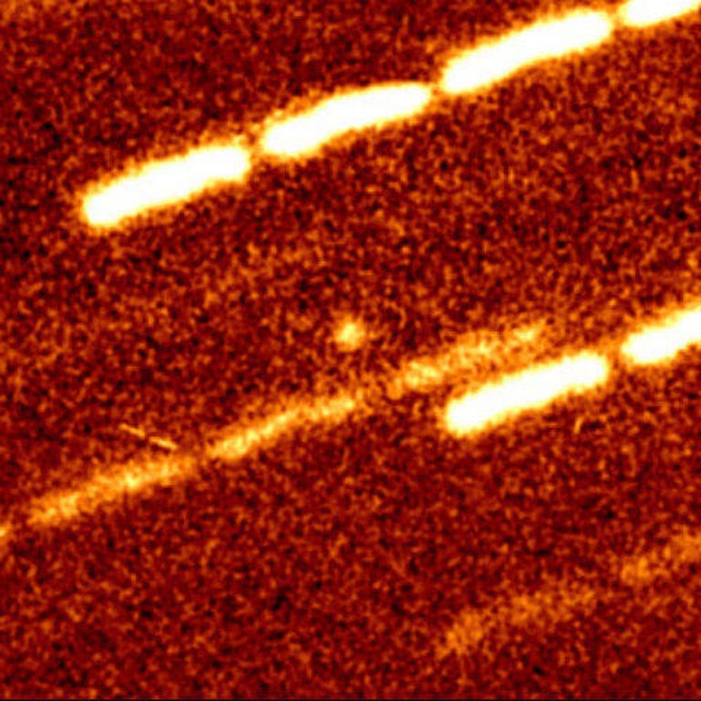 A small dot of light against a streaky red background shows an early look at a near-sun object before it developed a tail.