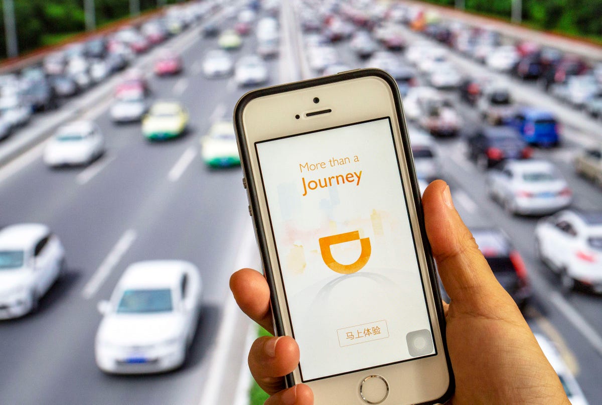 Hand holding a smart phone with an App of Didi Chuxing.