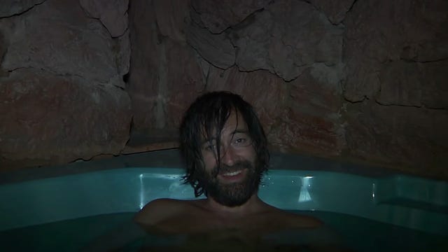 A man in a hot tub smiling creepily at camera