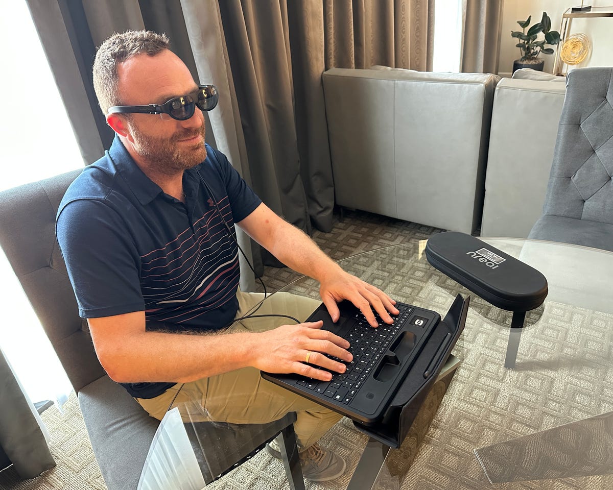 Hombre trabajando en una laptop sin pantalla con gafas de realidad aumentada