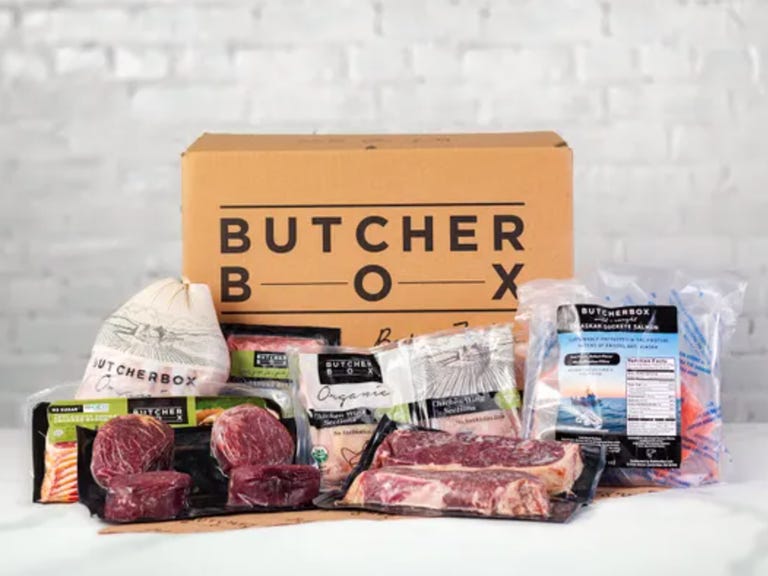 A collection of packaged meats in front of a cardboard box with the ButcherBox logo.