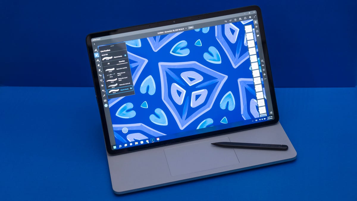 A Microsoft Surface Laptop with stylus against a blue background