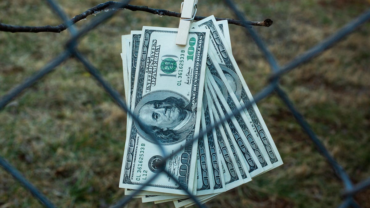 hundred dollar bills clipped with clothespin behind fence, inaccessible