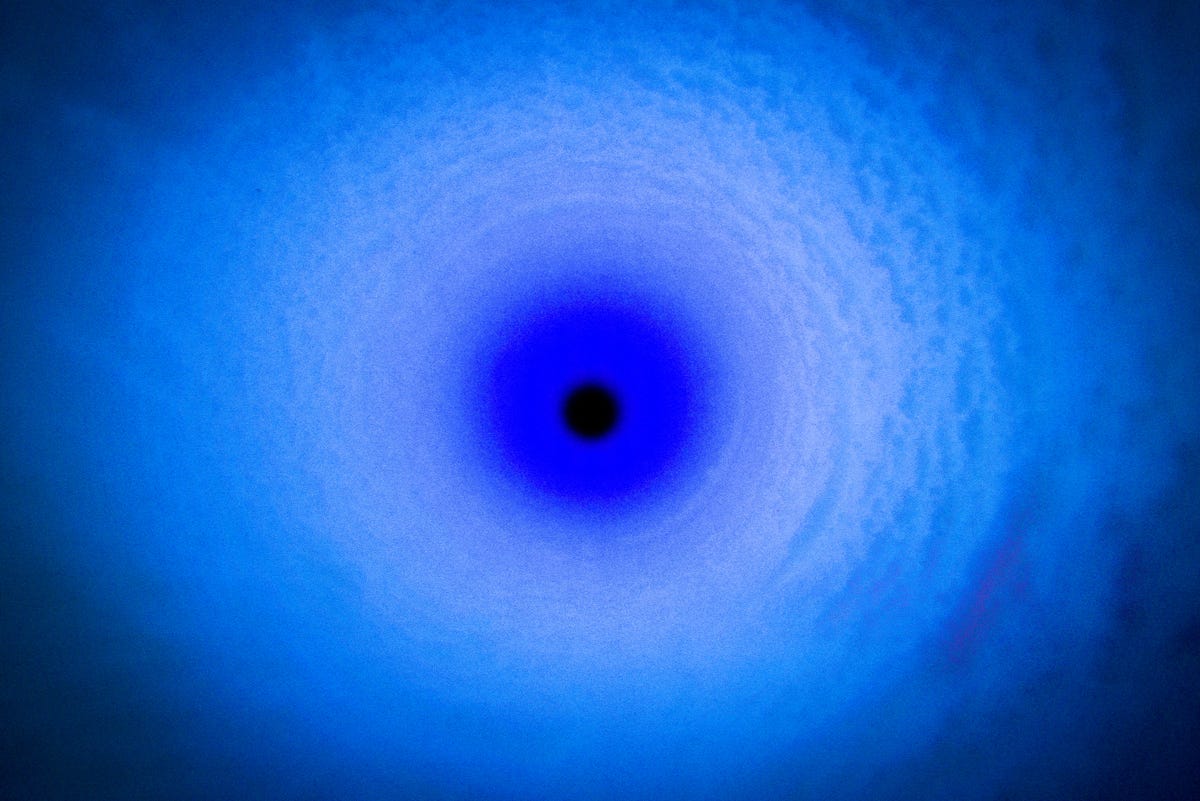 Looking down a borehole you see a small black circle at the centre of the image surrounded by rings of blue light