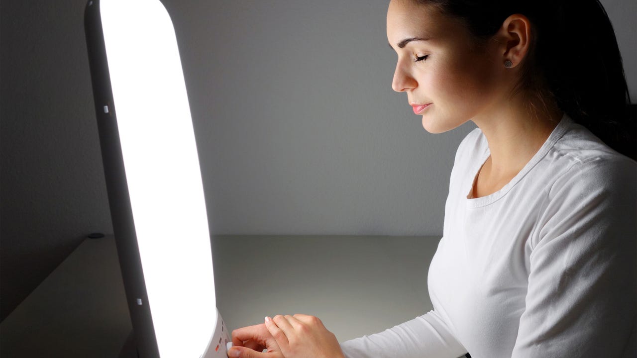 Woman using light therapy with a sun lamp to manage seasonal affective disorder