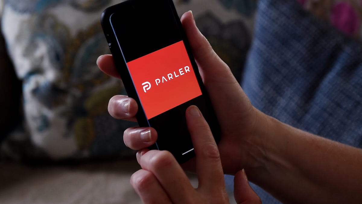 Hands holding a smartphone that is displaying a Parler logo