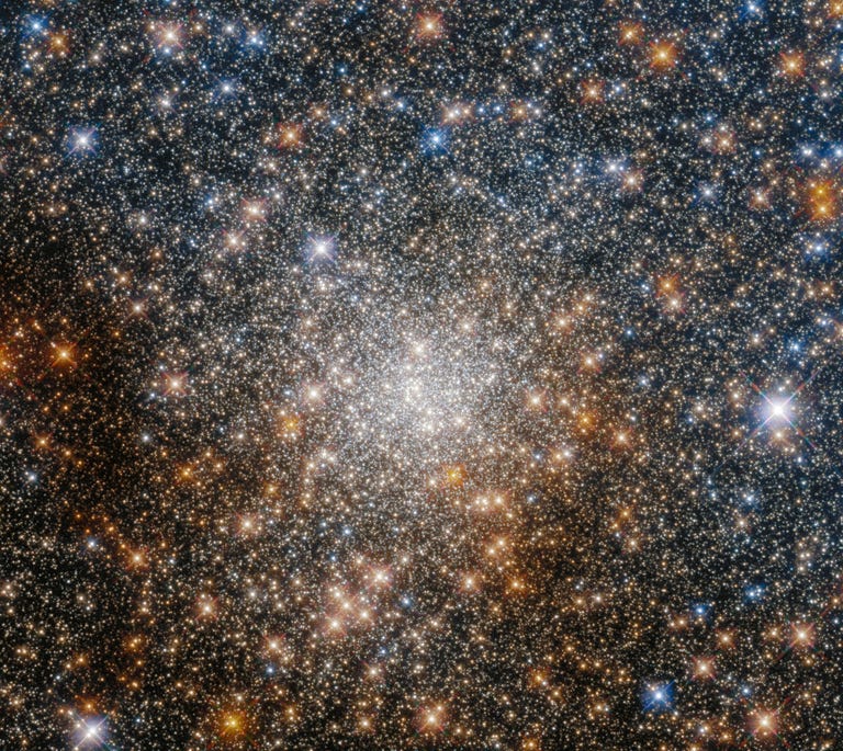 A sparkling blanket of stars against the dark of space with a dense, brighter area of glittering light in the middle.