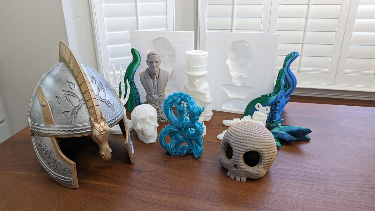 An assortment of models printed on the K1 and K1 Max. A helmet, dragon, and skull in front.