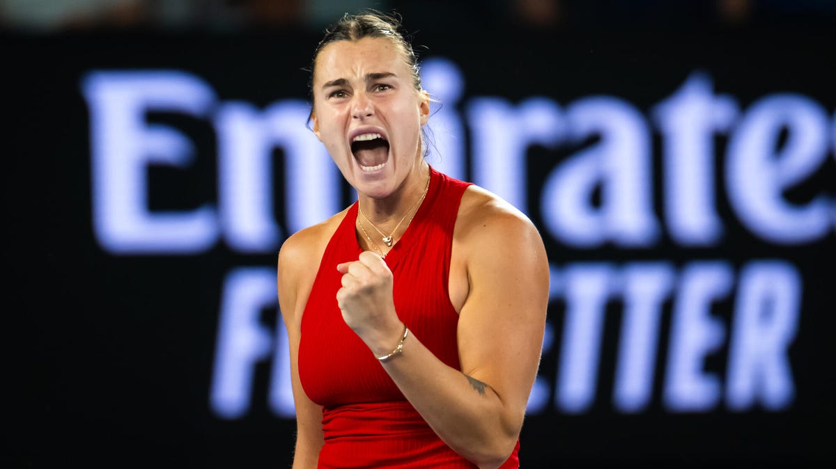 Tennis player Aryna Sabalenka celebrating with her left hand raised and clenched in a fist.