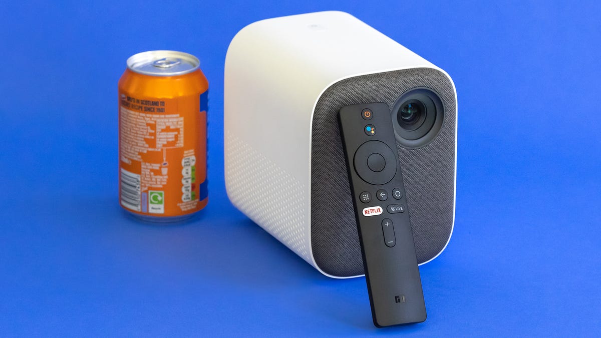 The Mi Smart Projector 2 is controlled with its thin remote next to an Irn-Bru soda can for scale.