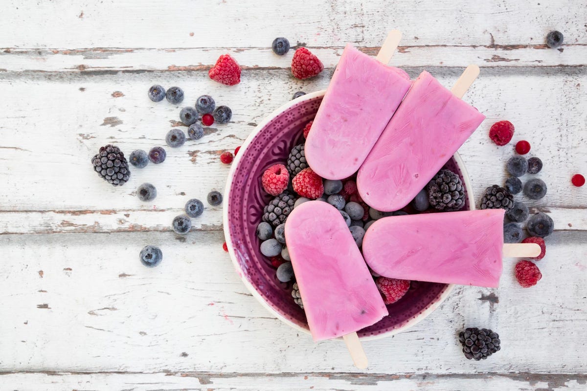 Homemade wild-berry ice lollies with raspberries, blueberries, red currants and blackberries in a bowl