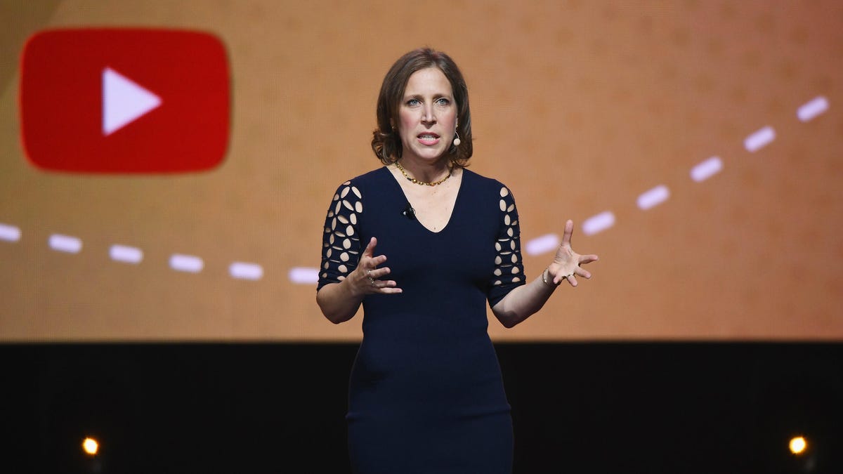 YouTube CEO Susan Wojcicky gestures on stage with the YouTube logo behind her