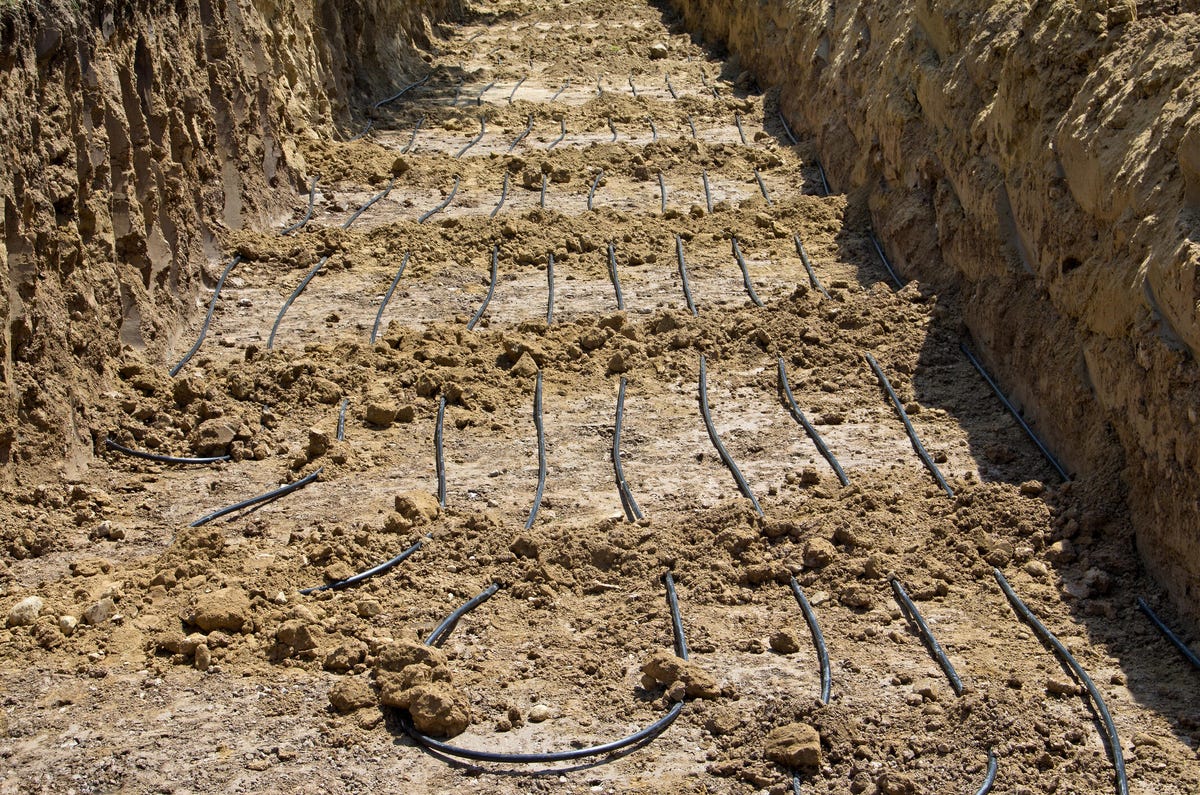 Thin black tubing in an open trench.