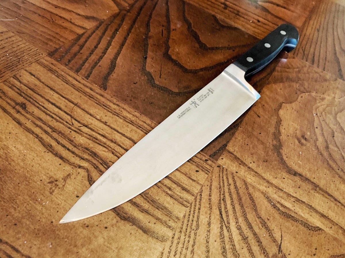 A J.A. Henckels' chef's knife on a wooden cutting board.