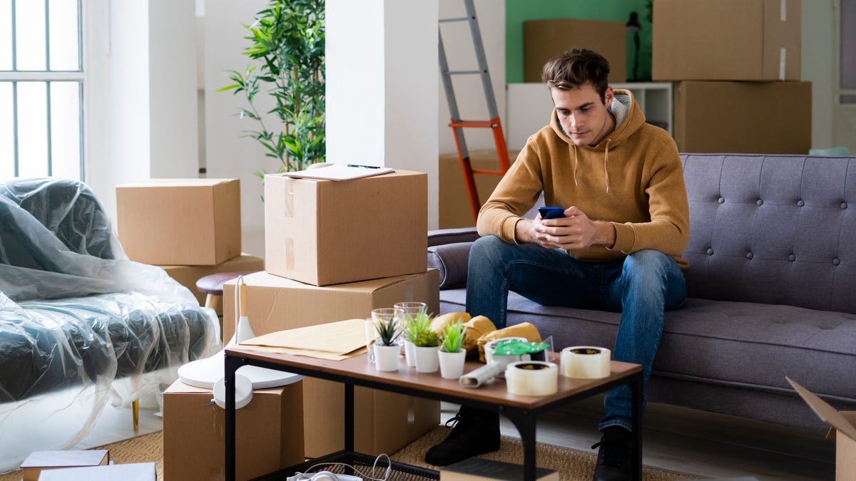 Man on phone sitting on couch with moving boxes