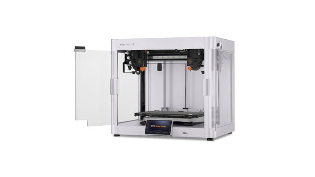 A silver 3D printer with two print heads and orange accents
