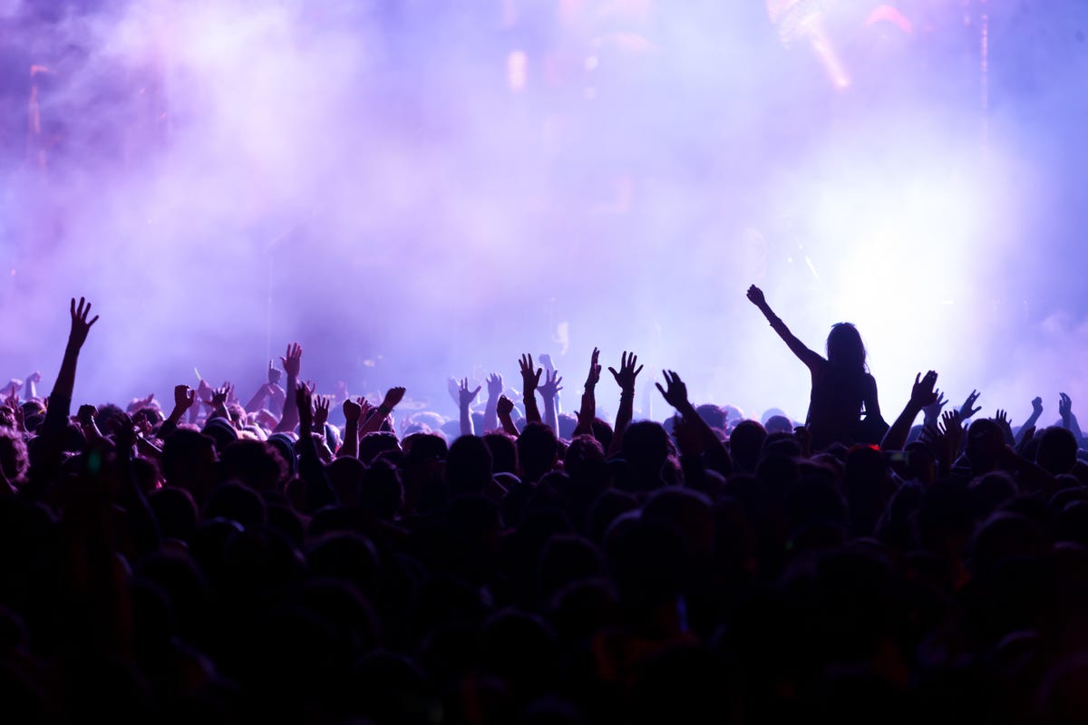 A crowd at a concert against a purple background