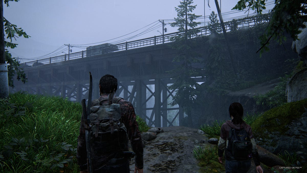 Joel and Ellie observe a bridge in a rural area in The Last of Us Part 1